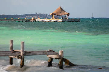 Rustic pier with thatched hut over turquoise waters in Puerto Morelos