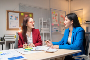 Two women are talking in a room with a bulletin board on the wall