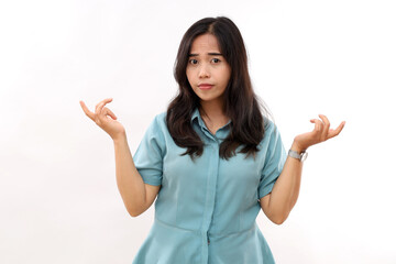 Puzzled questioned woman with dark hair clueless expression raises hands shrugs shoulders with bewilderment does't know how to act wears casual shirt isolated over white studio background