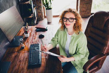 Photo of adorable positive lady broker wear shirt spectacles working modern gadget writing clipboard indoors workplace workshop