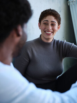 Man and woman sitting against a concrete wall having a conversation