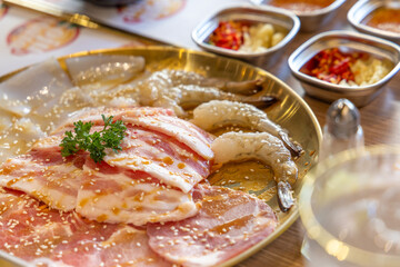 A set of pork, chicken, beef, squid, bacon, and pork belly for grilling in Thai style, called Moo Kratha or pork pan.