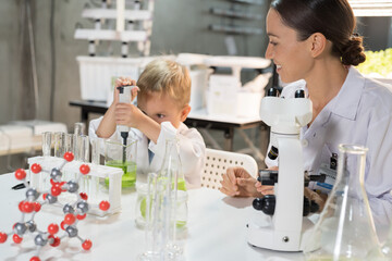Teacher and little child boy scientists learning science and doing analysis together in laboratory. Student and teacher learning science in classroom. Science and education concept