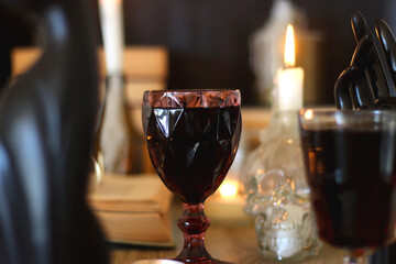 Books, lit candles, red wine, snacks and various deocration on the table. Dark academia or Halloween concept. Selective focus.