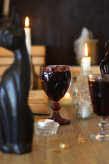 Books, lit candles, red wine, snacks and various deocration on the table. Dark academia or Halloween concept. Selective focus.