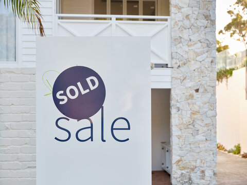 a real estate sign with sold sticker outside the house for sale