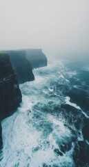 Misty cliffs along the rugged coastline with crashing waves and foggy atmosphere at dusk