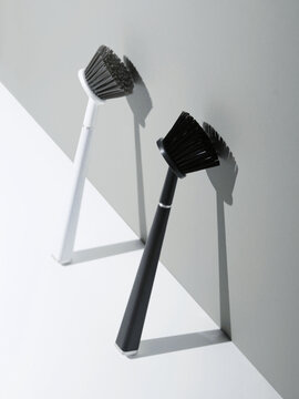 Pair of dish brushes leaning against grey wall