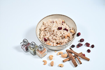 Bowl of rice, nuts, and spices arranged on a wooden table