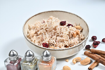 Bowl of rice, nuts, and spices arranged on a wooden table