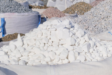 White marble pebbles are sold in construction market. Close up of materials pile. Building white...