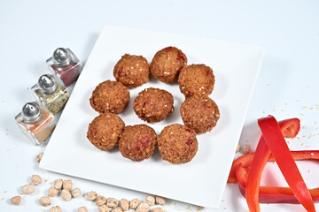 Closeup of red peppers, assorted nuts, and a plated meal on a white dish