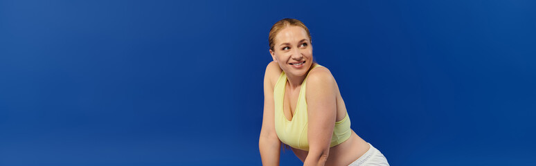 A cheerful woman in a crop top enjoys her workout, radiating energy in a colorful studio environment.