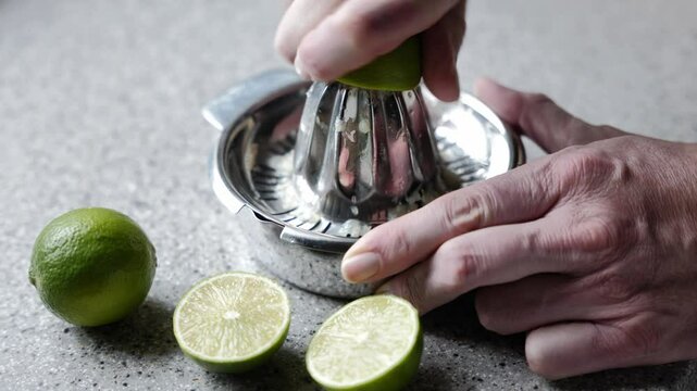 Auspressen einer Limette auf einer Zitruspresse.