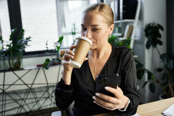 A vibrant plus size woman is engaged with her phone, sipping coffee in her office setting.