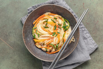 Glass noodles with vegetables and chicken in a bowl on the table. Asian cuisine