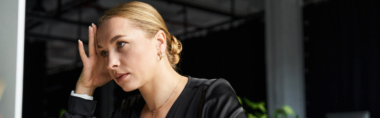 In a modern office space, a young plus size woman reflects deeply while at her desk.