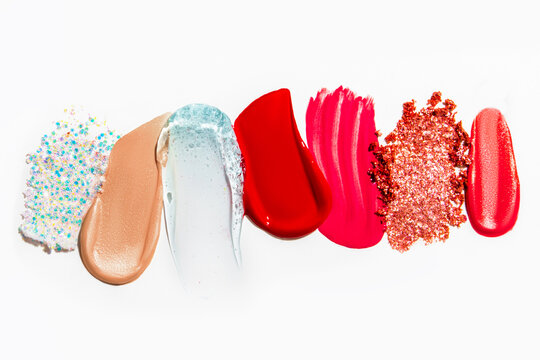 Set of cosmetic texture smears on a light background, including eyeshadow, lipstick, and glitter. Beauty products, vibrant and varied textures.