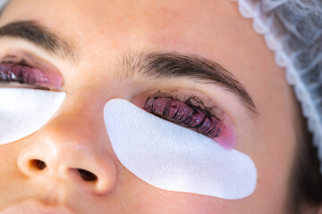 Woman during procedure of eyelashes lamination in beauty salon