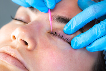 Woman during procedure of eyelashes lamination in beauty salon