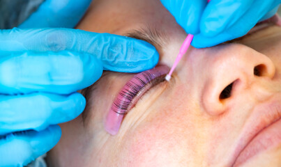 Woman during procedure of eyelashes lamination in beauty salon