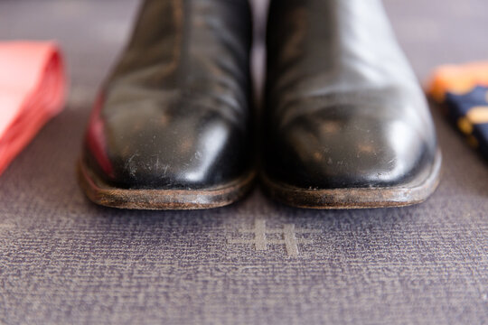black boots with lightly scuffed toes sitting on grey fabric