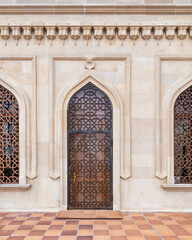 A beautifully crafted wooden door features an elaborate latticework design set against a...
