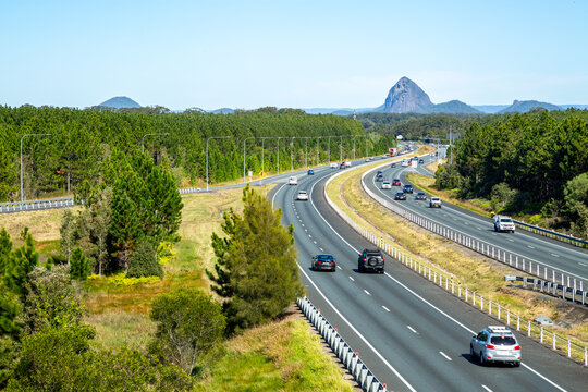 Vehicles driving the M1 Bruce Highway with glass house mountains in background.