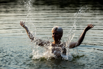 Happy woman in the sunset, splashing in the lake