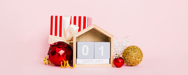 1 january. Christmas composition on colored background with a wooden calendar, with a gift box, toys, bauble copy space