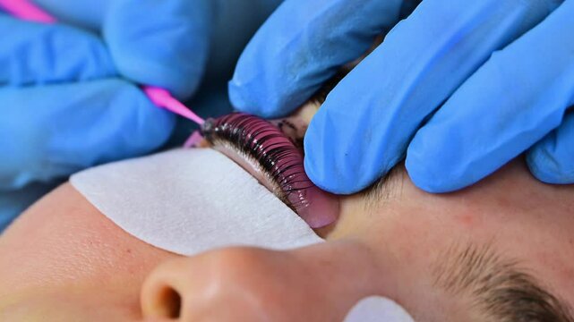 Woman during procedure of eyelashes lamination in beauty salon