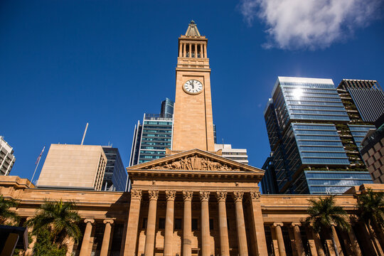 landscape photo of Brisbane city hall on a sunny day with blue sky and palm trees