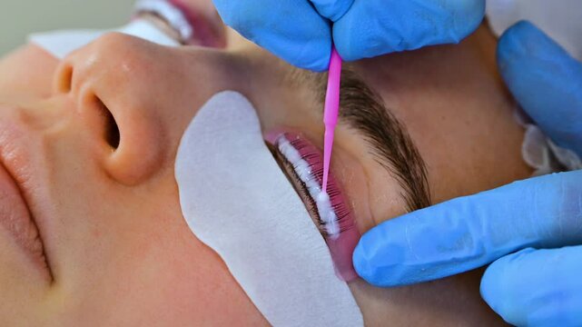 Woman during procedure of eyelashes lamination in beauty salon