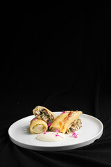 Stuffed Crepes with Mushroom Filling and Sour Cream on a White Plate.
