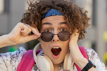 Oh my God, Wow. Happy young man taking off sunglasses looking surprised at camera with big open...