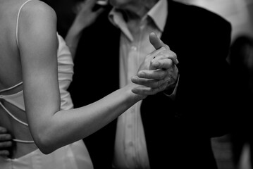 In an evocative black and white photograph, a man and a woman are seen joyfully dancing together, capturing a moment filled with movement