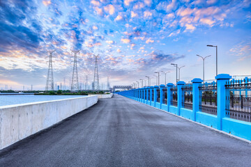 Fototapeta premium Empty asphalt road and electricity pylons at sunset