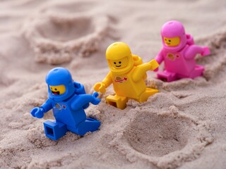 Naklejka premium Tambov, Russian Federation - July 28, 2024 Three Lego astronaut minifigures walking on sand surface. Focus on a yellow spaceman