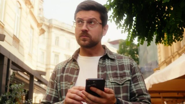 Caucasian man male tourist traveler confused guy walking street outdoors using mobile phone navigator going lost city smartphone gps map online app destination searching address location travel guide