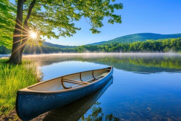 Obraz premium A Canoe Awaits on a Misty Morning Lake with Sunlight Filtering Through Tree Branches