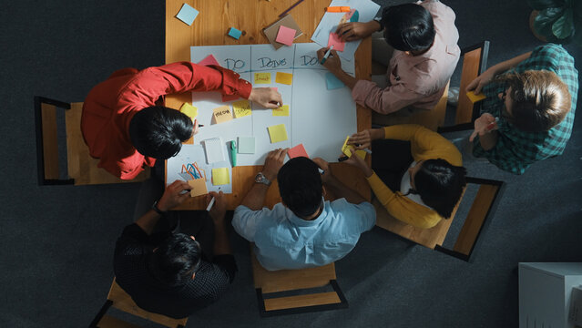 Top view of people writing and making scrum task board while writing marketing and planning strategy at colorful sticky notes. Smart team manage work performance by using kanaban board. Convocation.