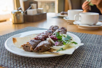 beef kebab served on a plate with onions and pita bread and sauce in a restaurant