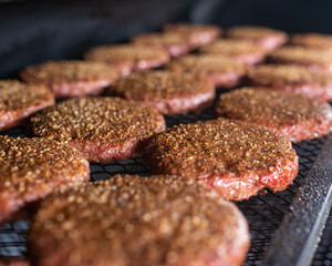 a hamburger on a raw grill plate with a hand holding the meat	