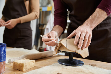 A couple shares a joyful moment shaping clay together.