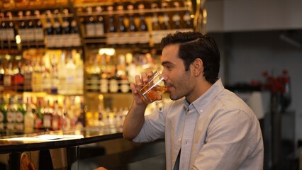 Smiling smart man drinking cocktail in Old fashioned with enjoy in cheers with friends or stranger sitting across special vibrant beverage at nightclub on Friday meeting at luxurious bar. Vinosity.