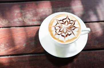 In the morning  hot latte art coffee is served on a wooden table