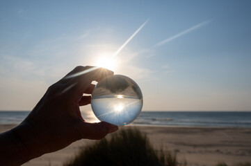 Beach and sea reflected in a ball in a human hand