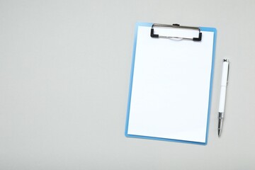 Clipboard with paper sheet and pen on gray background, top view. Space for text