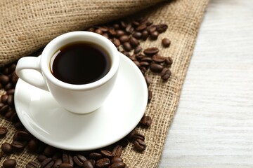 Cup of coffee and coffee beans on wooden background