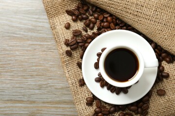 Cup of coffee and coffee beans on wooden background